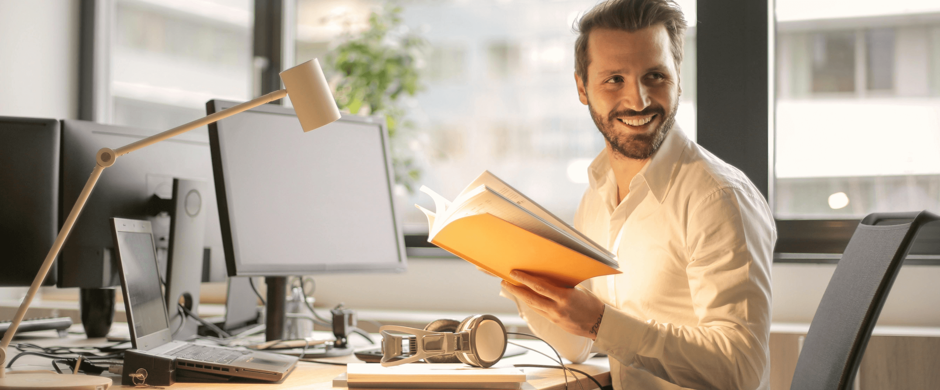 Mann sitzt am Schreibtisch und blättert durch einen Ordner